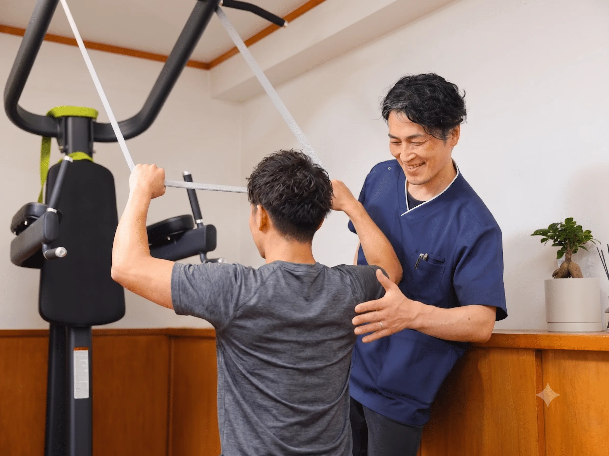 トレーニング機器を使う利用者にトレーナーがフォームを確認している様子